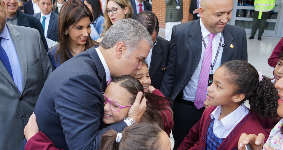 Foto de la Ministra María Victoria Angulo y el presidente Duque invitando a los niños a ingresar al colegio