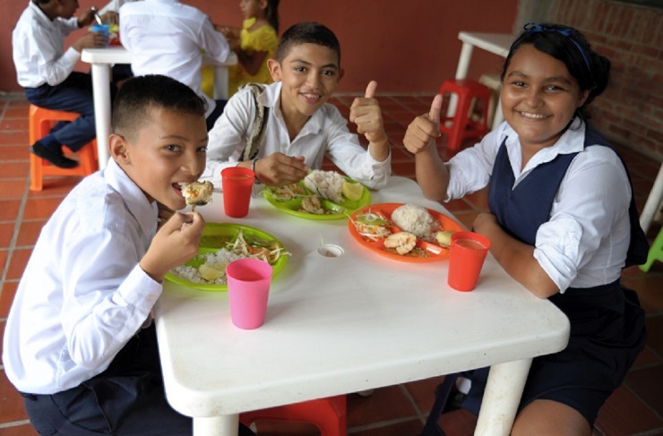 Tres estudiantes en comiendo alimentos del PAE