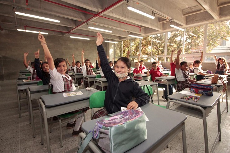Niños de la IE Enrique Vélez de Itagüí levantando la mano en salón de clases