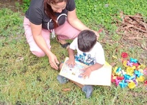 Niño aprendiendo a leer en zona rural junto a su profesora