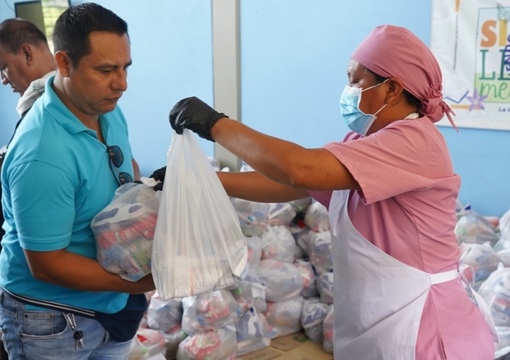 Mujer entrega alimento del PAE a padre de familia