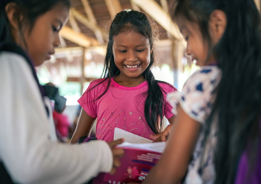 Niña sonriendo mientras ve un cuaderno