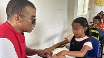 Profesor tiflologo guía a estudiante con discapacidad visual en la lectura del braille