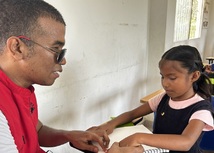 Profesor tiflologo guía a estudiante con discapacidad visual en la lectura del braille