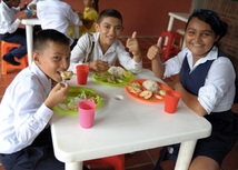 Tres estudiantes en comiendo alimentos del PAE